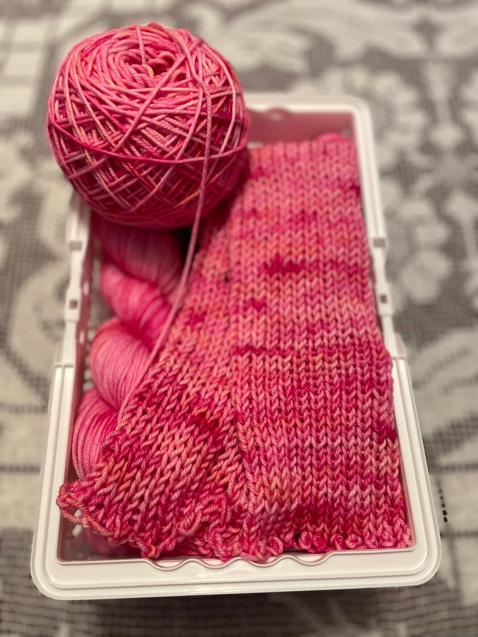 Pink hand dyed yarn ball and knitted swatch in Heart Rest colorway showing tonal variation.